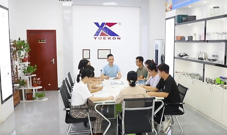 Gambar pertemuan di Zhongshan Yuekon Electrical Appliances Co., Limited, memperlihatkan anggota tim terlibat dalam diskusi bisnis.